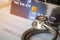 Stethoscope on Mock up Credit Card with number on cardholder in hospital desk. Health insurance and cost of care, self-care during