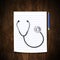 Stethoscope with pencil on wood background