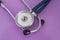 Stethoscope or phonendoscope lying on a purple background big head diaphragm, plastic disc upwards near the earpieces closeup