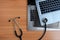 Stethoscope on pile of used laptops computer, on wooden background.Top view copy space