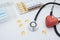 Stethoscope and red artificial heart, vitamins and pills, on a white background