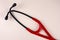 Stethoscope red and black on beige background. Real professional medical equipment. Healthcare, checkup, heart disease