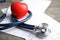 Stethoscope, red heart and cardiogram on gray table.