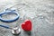 Stethoscope and red heart on grey textured background. Health care concept