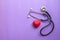 Stethoscope and red heart on purple background. Cardiology concept