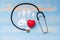 Stethoscope with Red heart shape, Family and House paper on blue pastel color wooden