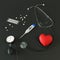 Stethoscope, red toy heart, tonometer, thermometer, pills on a dark background. 3d rendering