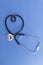 Stethoscope in the shape of heart on blue background