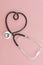 Stethoscope in the shape of heart on pink background