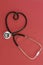 Stethoscope in the shape of heart on red background