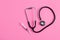 Stethoscope and syringe on pink pastel background