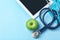 Stethoscope, tablet and apple on color background