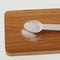 Stevioside in plastic measuring spoon on wooden board, close-up. Stevia sweetener. Food additive E960. Natural Extract, white