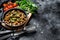 Stew with chicken hearts and vegetables with fresh parsley. Black background. Top view. Copy space