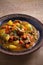 Stew, made with beef, potatoes, carrots and green peas. Goulash soup in a bowl on wooden table.