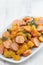 Stew sausages with sweet potato and vegetables on white dish