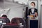 Stewardess carrying food trolley in airplane cabin
