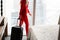 Stewardess in red uniform arrives in a hotel room with black suitcase. Rest in the transit city before the return flight