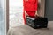 Stewardess in red uniform arrives in a hotel room with black suitcase. Rest in the transit city before the return flight