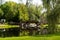 Stewart Park, a view of the red footbridge and old stone house surrounded by trees, view from pond in summer. Perth