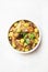 Stewed aubergines with vegetables and herbs in a bowl, light background, top view