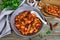 Stewed broad beans in tomato sauce with herbs and spices closeup. Slices of rye bread with beans on the wooden table.