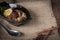 Stewed eggs and pork in black bowl and spices, spoon stainless steel place in front of on Sack and wood background