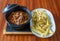 Stewed entrails, kidneys, navels and meat in sauce accompanied by fried potatoes on a tray in a plate on a wooden table.