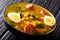 Stewed Potaje de garbanzos chickpeas, spinach, chorizo sausages, boiled eggs close-up in a bowl. horizontal