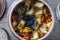 Stewed potato, carrot, onion, tomato and prunes in a clay pot on wooden background, closeup