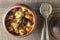 Stewed potato, carrot, onion, tomato and prunes in a clay pot on wooden background, closeup