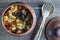 Stewed potato, carrot, onion, tomato and prunes in a clay pot on wooden background, closeup