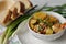 Stewed potatoes and chicken in a white plate. Green onions and pieces of bread next to it. Close-up