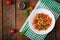 Stewed white beans with mushrooms and tomatoes with spicy sauce in a white bowl.