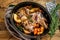 Stewed whole lamb shoulder in a baking dish. Wooden background. Top view