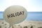 Stick with paper speech bubble with words Holiday on background blue sea