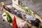 Stick of smoked sausage on cutting board with leaves of rosemary