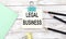 Stickers with pencils and notebook with text LEGAL BUSINESS on wooden background