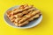 Sticks of buttery yeast dough on a plate on a yellow background
