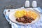 Sticky Indian style spiced chicken with a side dish of boiled potatoes and fresh cabbage salad on a white clay plate