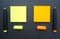 Sticky notes in yellow and orange color with marker pens in the same color on the black board background