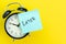 Sticky post with handwriting the word Later stick on alarm clock on solid yellow background with copy space using as