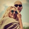 Stilish couple walking in modern dresses and trendy sunglasses on summer background. Beautiful female blond model with hoody on