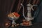 Still life with Ancient East metallic crockery - vintage jug, vase with dried fruit and plate with tea in armuda glasses