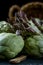 A still life of artichokes with knife and asparagus on the rustic textured background macro dramatic view