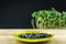 Still life black seeds sunflower in green plate on wooden platform.