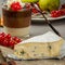 Still life with blue cheese, layered chocolate dessert in glass, cranberry and pear