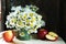 Still life with bouquet of daisies and red apples on white tablecloth.