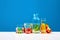 Still life with broccoli, red and yellow pepper on table with bottle of water over blue studio background. Nutrients