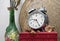 Still life with broken alarm clock, old glass vase with dead rose, classic perfume, vintage box.